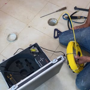 אדם מחזיק כבל צהוב ליד מזוודה עם ציוד איתור נזילות