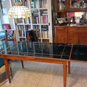 שולחן עץ עם משטח זכוכית כהה בחדר אוכל