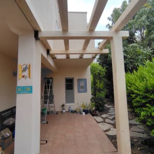 פרגולה מעץ בהתקנה בחצר עם צמחים מסביב