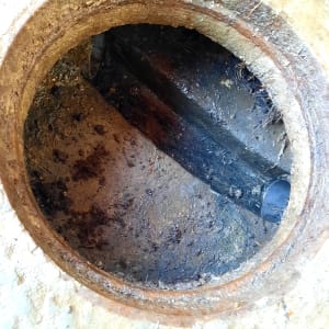 פתח ביוב עם צינור מתכת חלוד