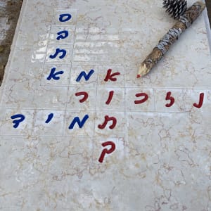 מצבה עם כיתוב בעברית וענף עם אצטרובל