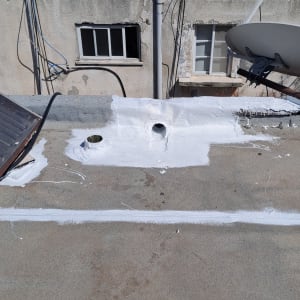 גג עם צינורות וכתמי צבע לבן