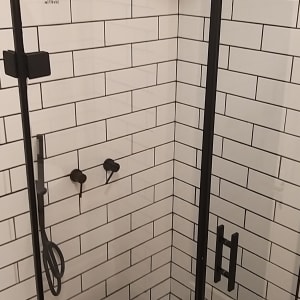 מקלחון עם אריחים לבנים ודלת זכוכית