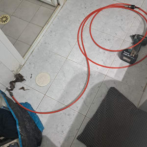 כבל אדום על רצפת חדר אמבטיה ליד מקדחה
