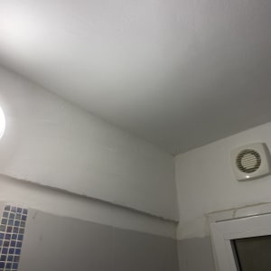 מנורה עגולה על קיר לבן עם מאוורר קטן