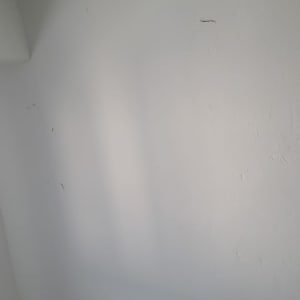 קיר לבן עם סימני צבע ותיקונים