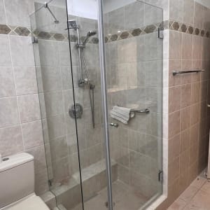 מקלחון זכוכית עם ראש מקלחת ומגבת תלויה