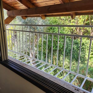 מרפסת עם מעקה מתכת לבן וחלון פתוח