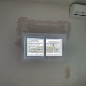 חלון אלומיניום עם סורגים על קיר לבן