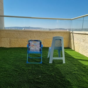 דשא סינתטי על מרפסת עם כיסאות פלסטיק