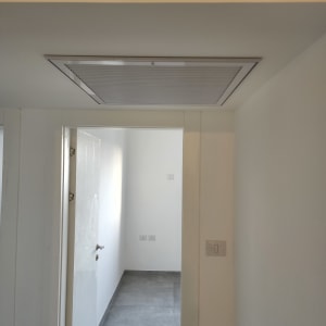 פתח מיזוג אוויר בתקרה עם תרמוסטט על הקיר