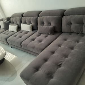 ספה אפורה עם כריות לבנות על ריצוף מבריק