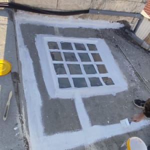 אדם צובע מסגרת חלון בגג עם מברשת וצבע לבן