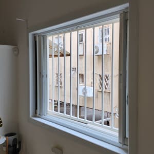 חלון עם סורגים לבנים בתוך מסגרת לבנה