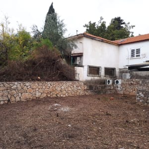 שטח אדמה עם ערימת גזם ליד קיר אבן