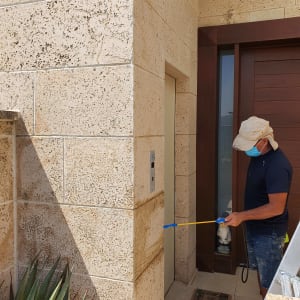 אדם מרסס חומר איטום על קיר חיצוני