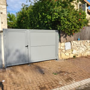 שער מתכת אפור על מדרכה מרוצפת