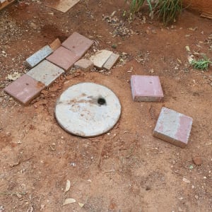 מכסה ביוב עגול על אדמה עם אריחים מסביב