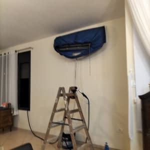 מזגן מכוסה בכיסוי כחול עם סולם לידו