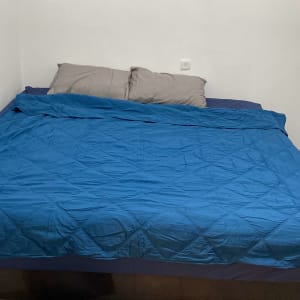 חדר שינה עם מיטה זוגית, כריות ושמיכה כחולה