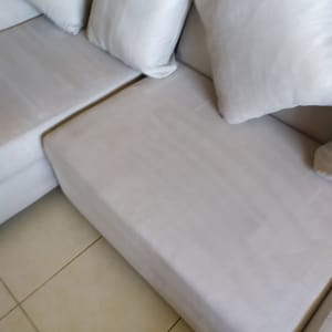 ספה בהירה עם כריות על רצפת אריחים