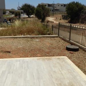 אדם עובד בגינה עם כלי עבודה ליד גדר מתכת