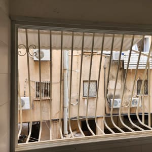 סורגים לבנים על חלון עם נוף חיצוני