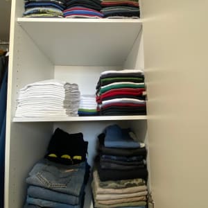 בגדים מקופלים בארון לבן בשלוש קומות