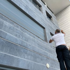 אדם מנקה חלונות עם מגב על בניין גבוה