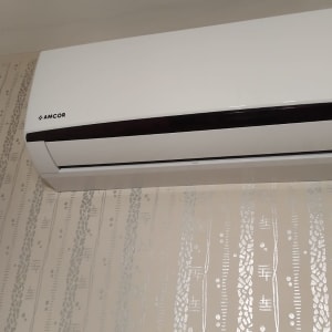 מזגן קיר לבן מותקן על קיר עם טפט מעוצב