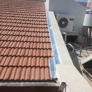 רעפים חומים על גג עם תעלה מתכתית