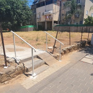 מעקה מתכת לבן ליד מדרגות בטון קטנות