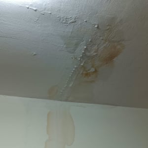 כתם רטיבות על תקרה לבנה עם סימני נזילה