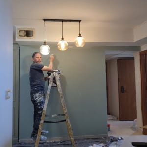 אדם צובע קיר בעזרת מברשת על סולם