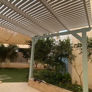 פרגולה מעץ עם צמחים מסביב בגינה