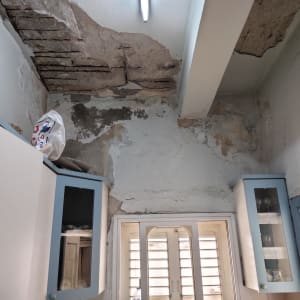 קיר מתקלף עם טיח מתפורר ותקרה פגומה