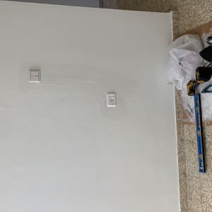 כלי עבודה חשמליים על הרצפה ליד קיר עם מתג ושקע