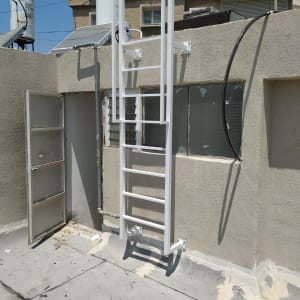 סולם מתכת לבן מותקן על קיר בטון