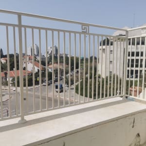 מעקה מתכת לבן עם קיר מתקלף