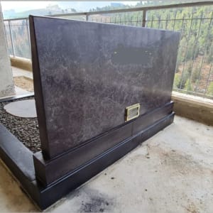 מצבה שחורה עם לוחית מתכת על בסיס בטון