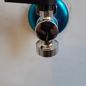 ברז מתכת עם ידית שחורה על קיר לבן