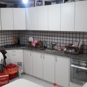 מטבח עם ארונות לבנים, כיור, ותנור אפייה