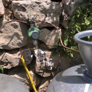 שסתום גז ירוק מחובר לצינורות על קיר אבן