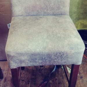 כיסא מרופד עם רגלי עץ על רצפת עץ