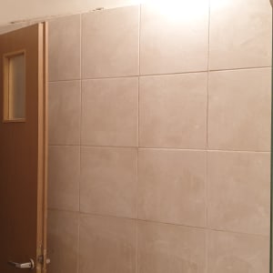 קיר אריחים עם דלת עץ פתוחה ומכשיר תלוי