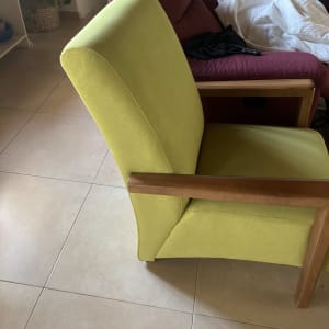 כורסה ירוקה עם ריפוד עבה וידיות עץ