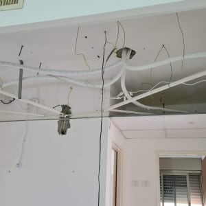 תקרת גבס פתוחה עם חוטי חשמל וצינורות חשופים
