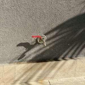 ברז מים עם ידית אדומה על קיר אפור