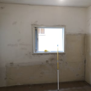 קיר עם סימני תיקון ומוט צביעה צהוב