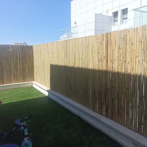 גדר במבוק על דשא סינתטי עם אופניים